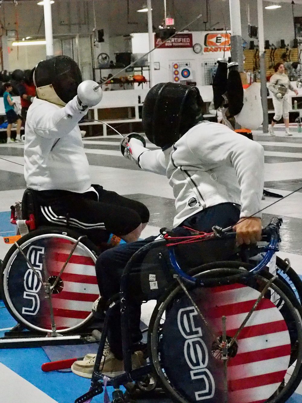 Two wheelchair fencers in an epee bout at Nova
