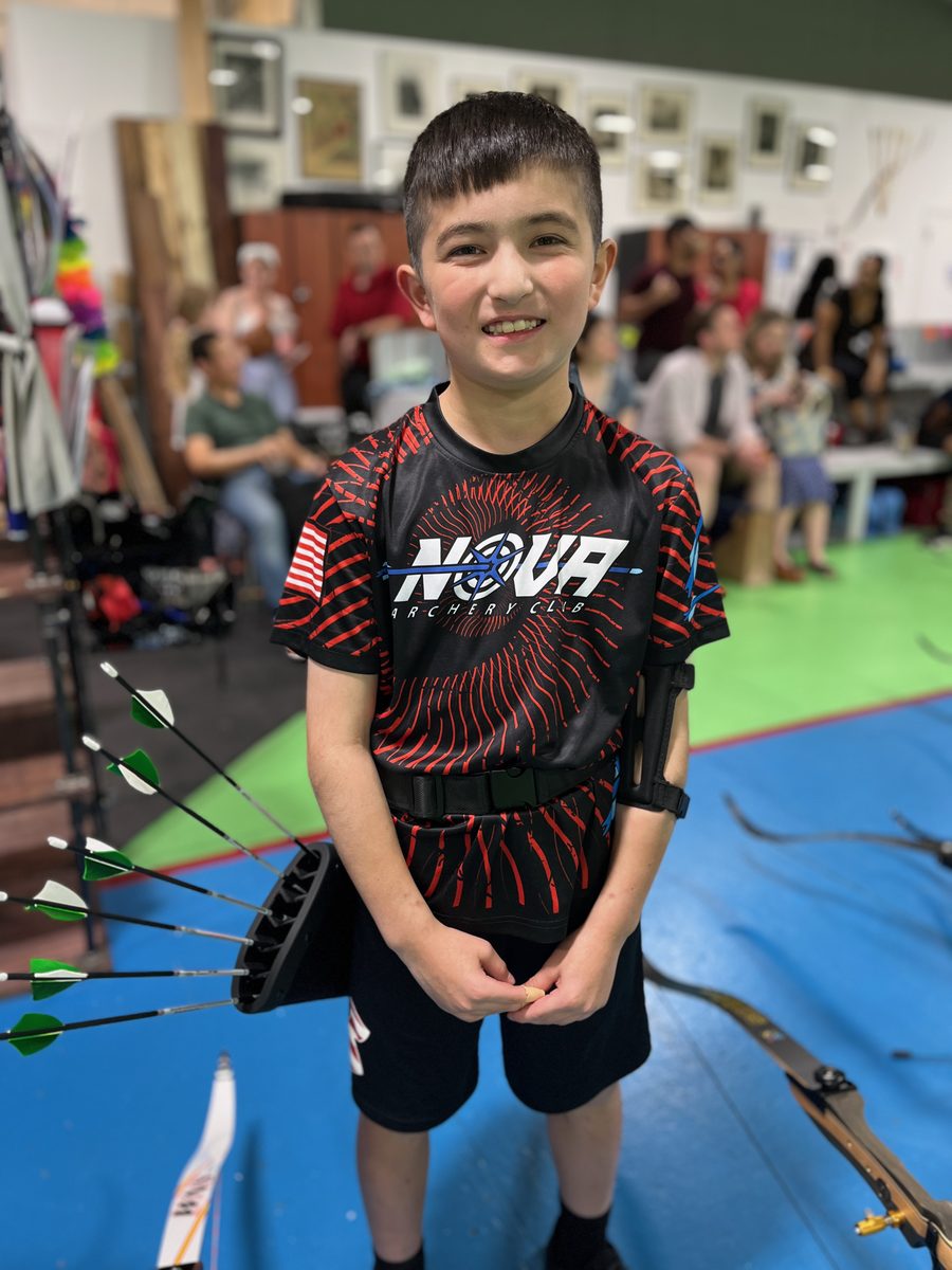 Youth archer with quiver and arm guard at Nova's indoor range