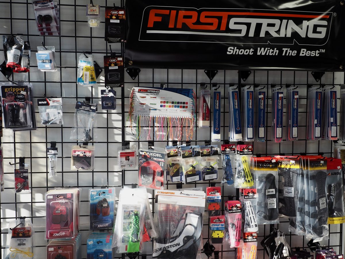 Tabs, sights, arm guards, and string accessories on the shop wall